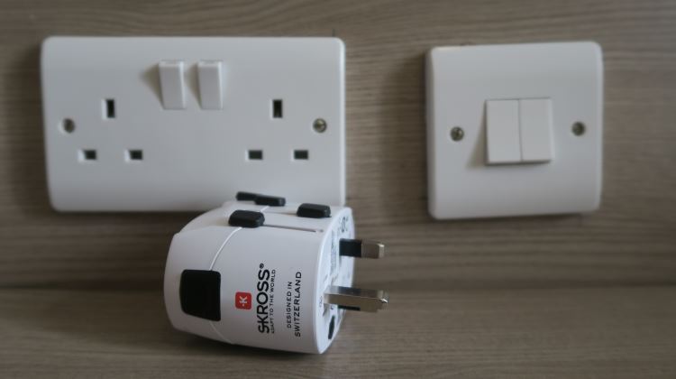 Zum Skross Pro Reisestecker für Malta auf Amazon! Eine weiße Steckdose - Stecker Typ G, auch genannt „BS 1363“ oder „British 3-Pin mit zwei Steckern auf Malta. Davor liegt ein Reiseadapter von Skross und es ist ein Lichtschalter auf dem Bild zu sehen.