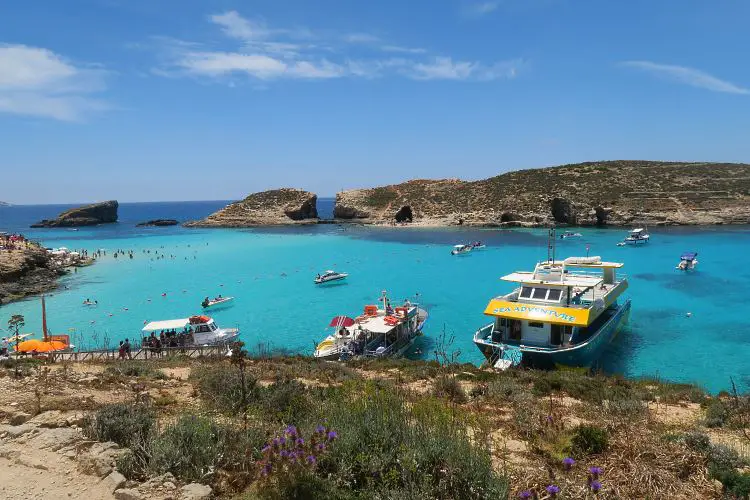 Der Blick auf die vor Anker liegenden Schiffe in der Blauen Lagune an der Insel Comino in Malta. Darin sind öffentliche Fähren und Ausflugsschiffe zu sehen. 