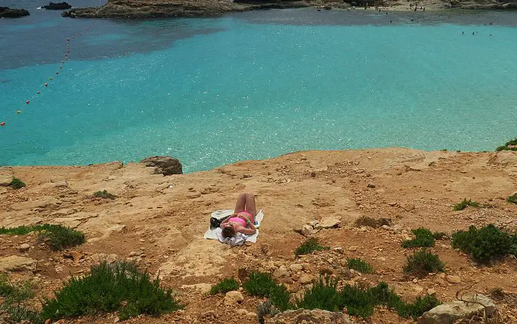 Daria liegt am Steinstrand an der türkisblauen Lagune auf Maltas Nachbarinsel Comino. Auf dem Bild sind keine anderen Badegäste in der Nähe zu sehen. Das ist für die Blaue Lagune ungewöhnlich. 