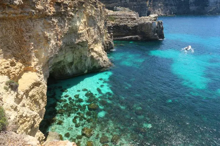 Das türkislblau Wasser unterhab der Klippen von Comino. An den Klippen befindet sich ein Felsebogen, der eine wunderschöne, blaue Grotte bildet. 