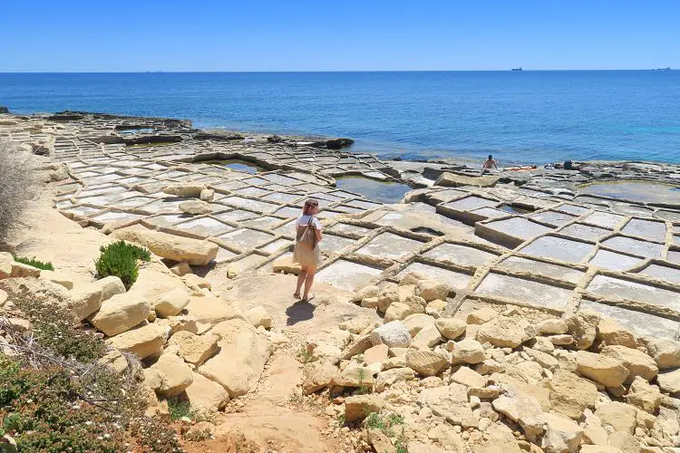 Daria steht an den Salzpfannen aus Stein, an der Küste von Marsaskala auf Malta. 