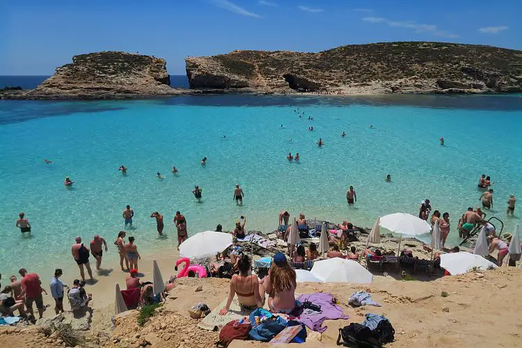 Reisende und Einwohner von Malta schwimmen im türkisblauen Wasser der Blauen Lagune auf Comino. 