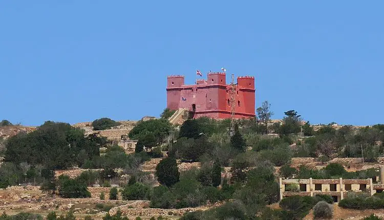 Der rote St Agatha’s Tower mit seinen vier Türmen, auf einem Hügel oberhalb der Mellieha Bay auf Malta.