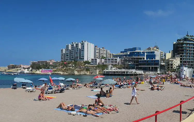 St. George´s Bay auf Malta im Frühling DEr gut besuchte Sandstrand, mit vielen Badegästen und die dahinterliegenden Hotels.