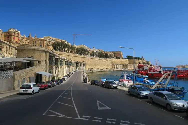 Eine zweispurige Straßen zwischen den Stadtmauern von Valletta und dem Hafen, der direkt am Meer liegt.