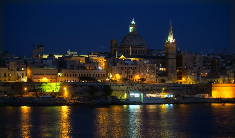 Blick von Sliema über den Marsamxett Hafen auf die hell erleuchteten Straßen in Valletta in der Nacht.