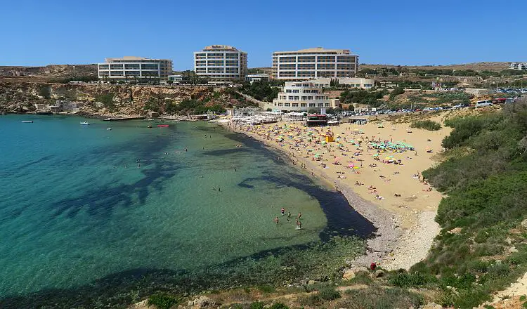 Das türkisblaue Meer am Golden Bay Sandstrand und das dahinterliegende Radisson Blu Resort Hotel. 