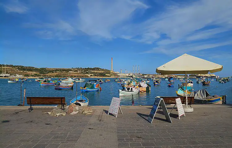 Marsaxlokk Hafen Luzzu Boote Blick von der Hafenpromenade aufs Meer hinaus.