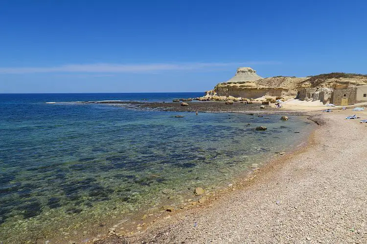 Ein Kieselstrand und das türisblaue, seichte, ruhige Meer. 