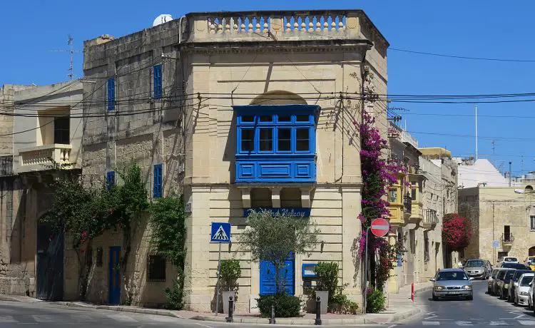 Ein sandfarbenes Haus mit blauen Fensterläden und Türen